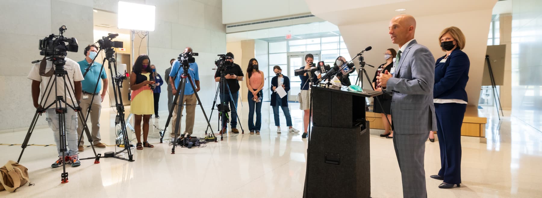 In the lobby of the School of Medicine, Dr. Alan Jones addresses a pool of reporters and accompanying videographers as Dr. LouAnn Woodward looks on. In the lobby of the School of Medicine, Dr. Alan Jones addresses a pool of reporters and accompanying videographers as Dr. LouAnn Woodward looks on.